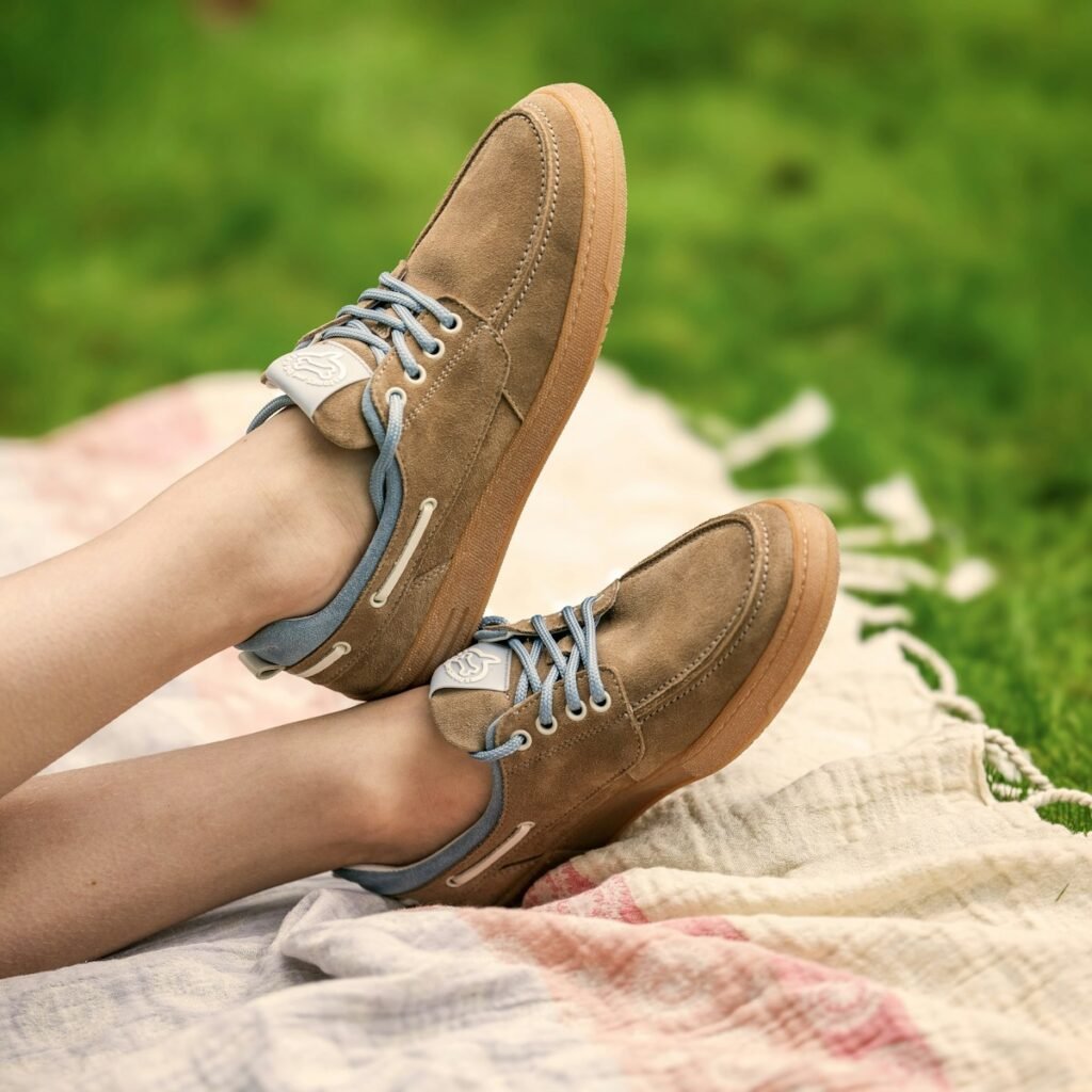 Stylish shoes resting on a blanket in grass.